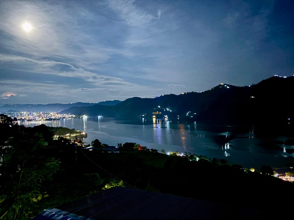 Night view of Pokhara city lights reflected on Phewa Lake with mountains in the background