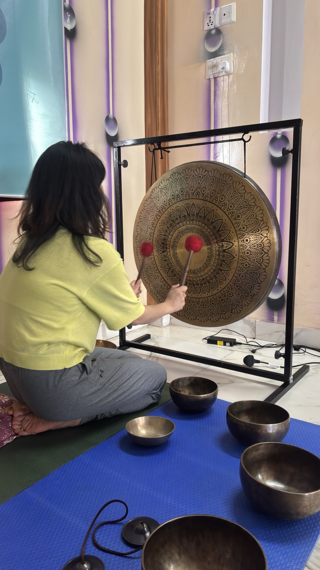 A girl from Taiwan learning to play gong and Himalayan singing bowls at Unmani Yoga Retreat in Pokhara Nepal